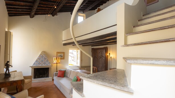 A cozy living room with a fireplace, a staircase, and a sofa. - Amazing Fontana di Trevi (Roma)