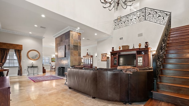 A spacious living area with a large leather sofa, a fireplace, and a staircase with ornate railings. - Mason Villa in Tampa (Tampa)