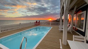 A pool on a deck with a sunset view. - Experience luxury at '7 Day Weekend,' an oceanfront 7-bedroom retreat in Oak Island. (Oak Island)