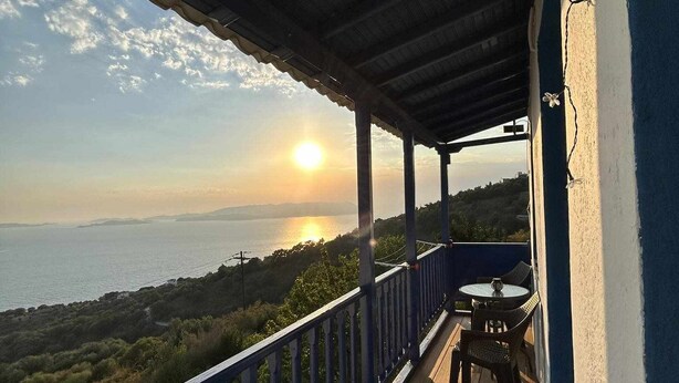 Una terraza de madera con barandilla, con vista a un cuerpo de agua y follaje.