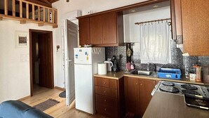 Una cocina compacta con armarios de madera, un refrigerador, una estufa y un lavamanos.