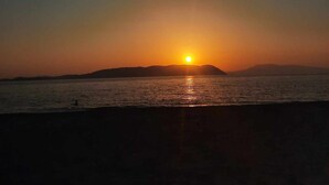 Un atardecer sobre un mar tranquilo con una masa de tierra a lo lejos.