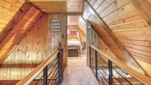 A wooden interior with a staircase leading to a bedroom.