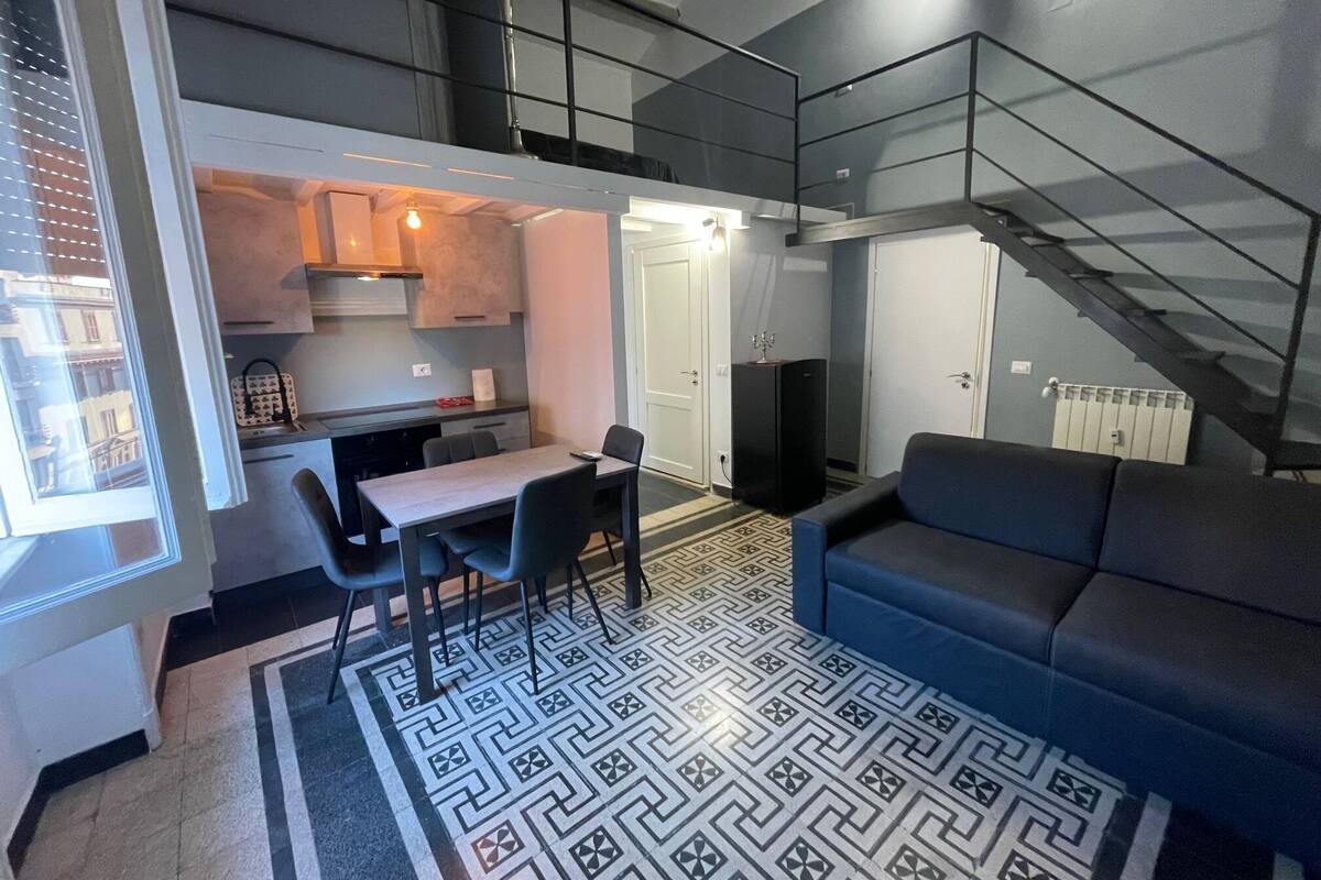 A compact living space with a kitchenette, dining area, and a staircase.