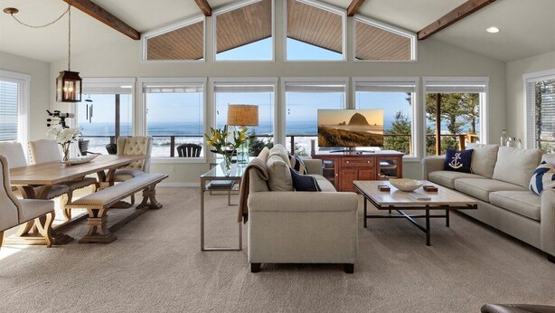 Un salón amplio con techo alto, ventanas grandes y vista al océano.