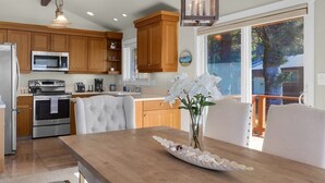Una cocina moderna con armarios de madera, electrodomésticos de acero inoxidable y un comedor con mesa y sillas de madera.