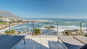 Une terrasse offrant une vue sur l’océan et la côte rocheuse.