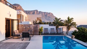 Un espace piscine avec des chaises longues et une vue sur les montagnes.
