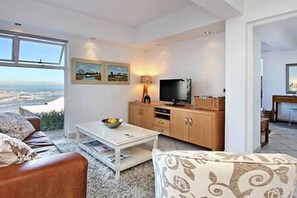 Una sala de estar moderna con un ventanal grande, un televisor y una zona de comedor.
