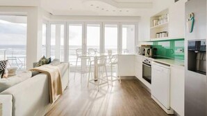 A modern kitchen with white cabinetry, a green countertop, and a stainless steel refrigerator. - Beautiful Holiday Apartment Overlooking the Beach Modoco (Cape Town)