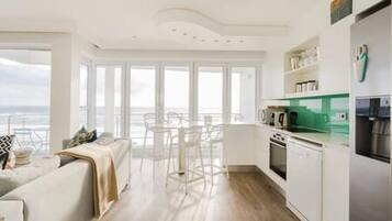 A modern kitchen with white cabinetry, a green countertop, and a stainless steel refrigerator.