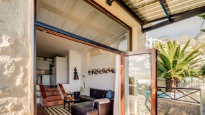 An open living area with a sofa, a coffee table, and a rug. There is a staircase leading to an upper level. - Camps Bay Holiday Apartment w Private Pool CBT Palm Suite (Cape Town)