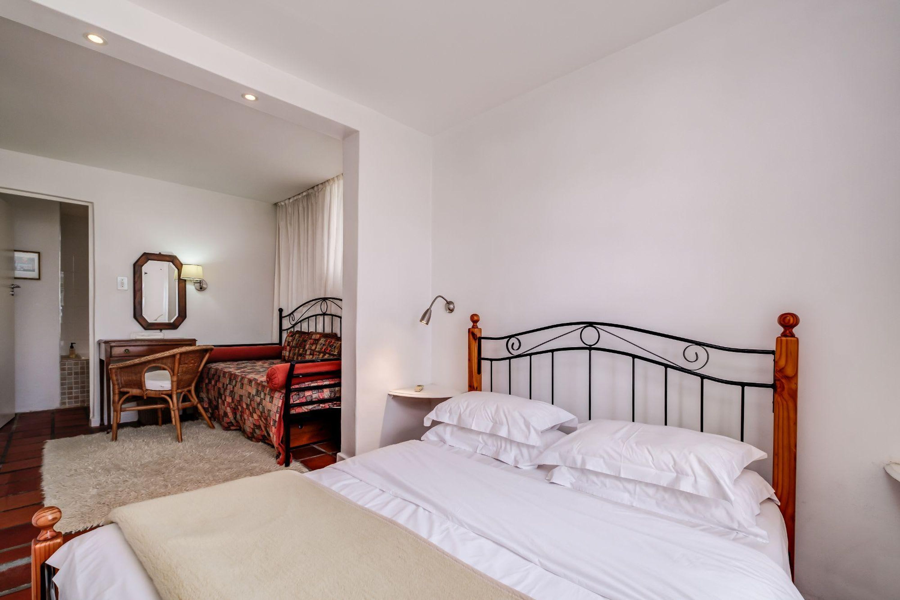Une chambre à coucher avec un lit en bois, un bureau, une chaise et un miroir.