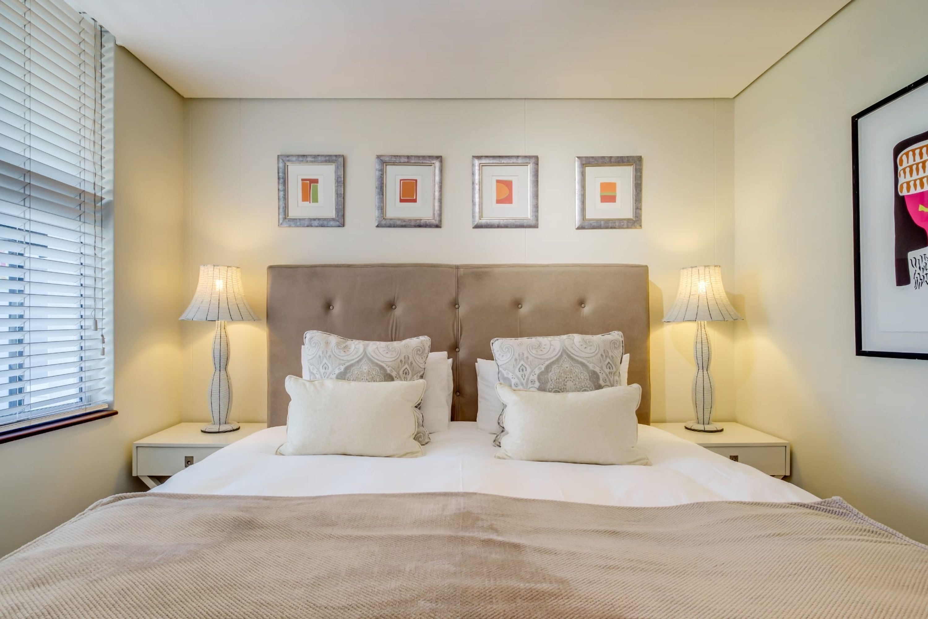 Una habitación de hotel ordenada con una cama grande, dos mesitas de noche y un cabecero.