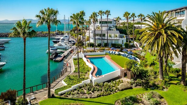 Ein Resort mit Swimmingpool, Palmen und einer Marina mit Booten.