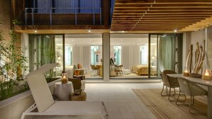 Een modern interieur met een zithoek, een eethoek en een slaapkamer, zichtbaar door glazen deuren.