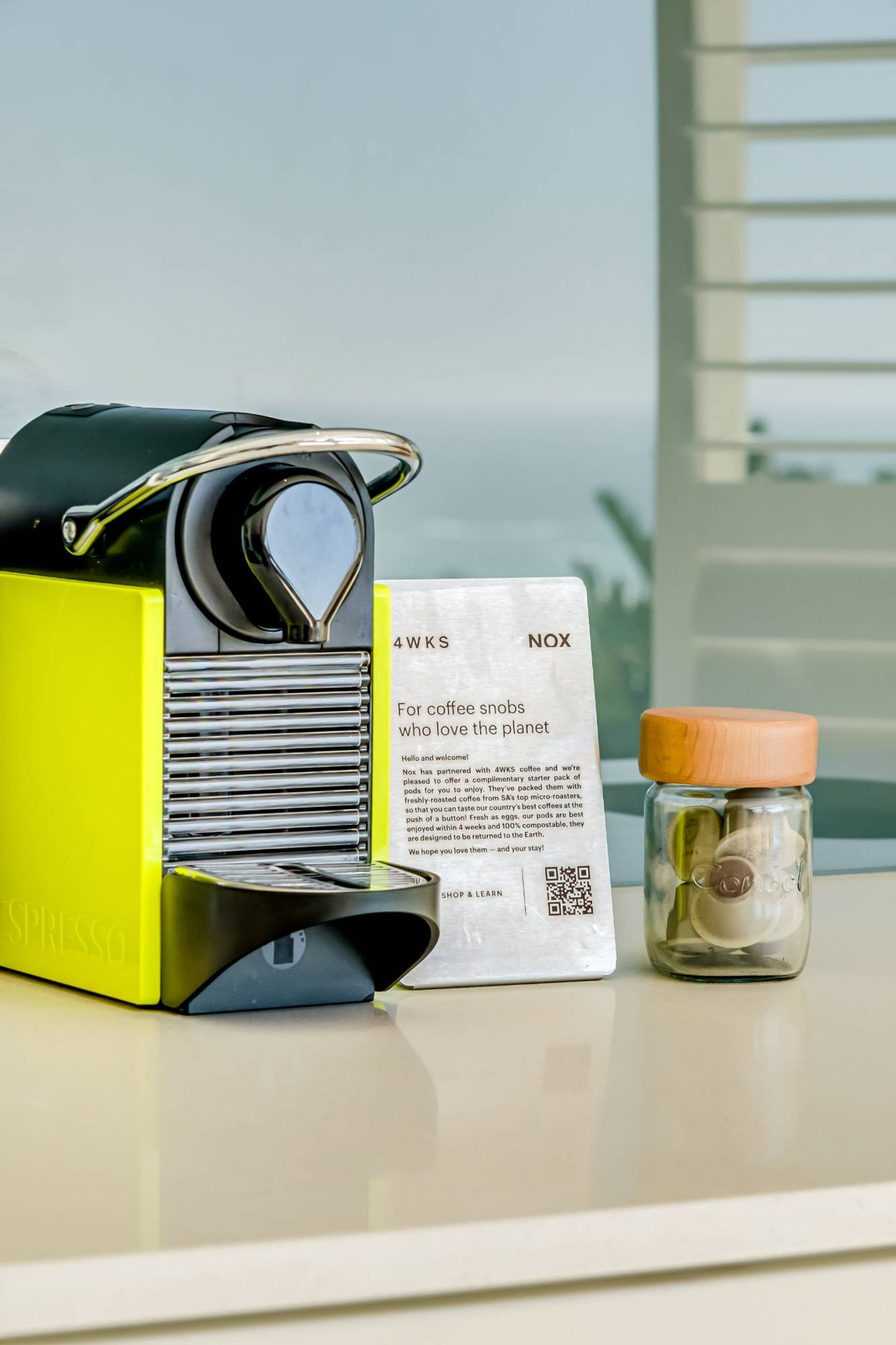 Een koffiezetapparaat, een pak koffiecups en een pot koffiebonen op een tafel.