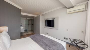 A modern hotel room with a large bed, a TV mounted on the wall, and a walk-in closet.