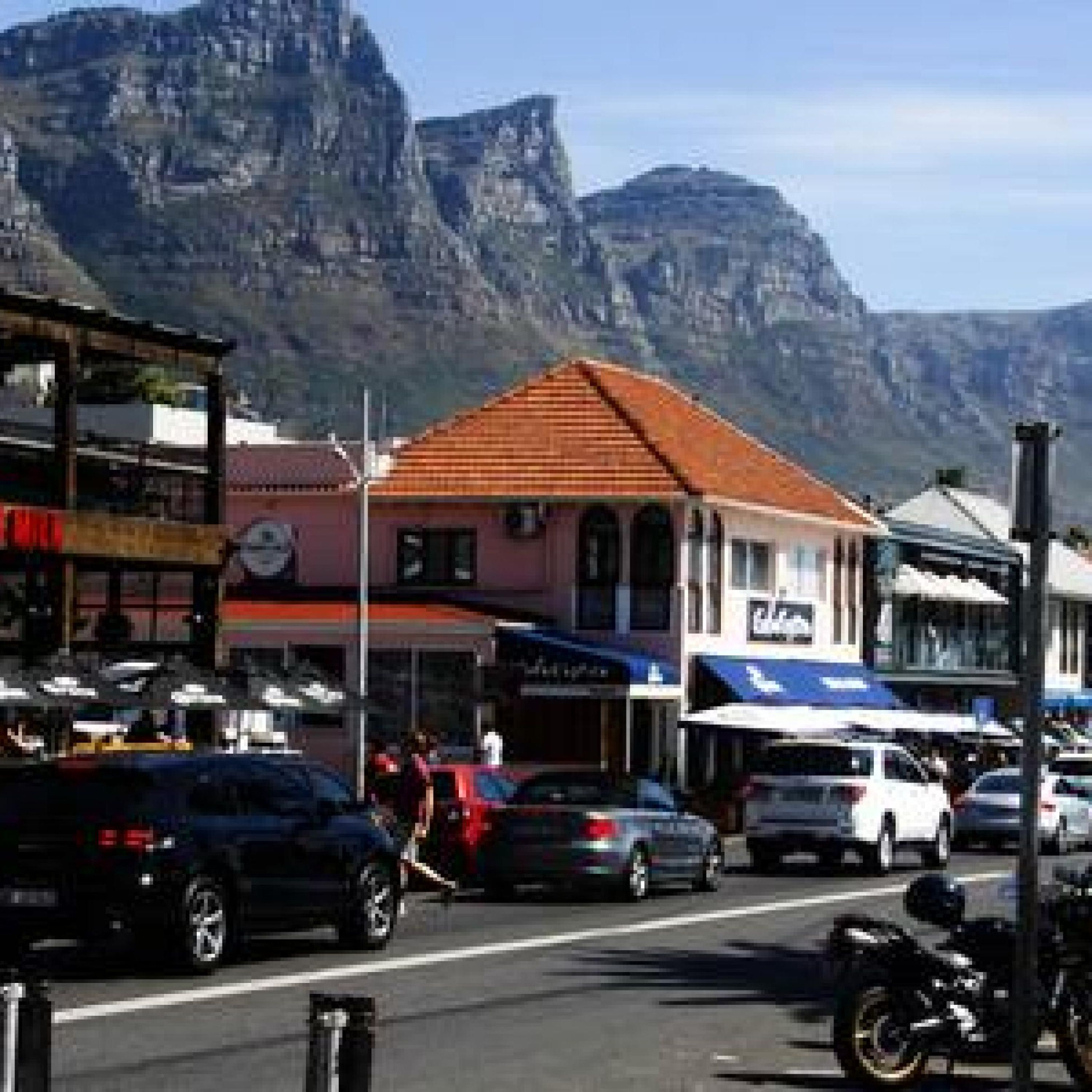 Une vue de rue avec des bâtiments, des voitures et une montagne en arrière-plan.