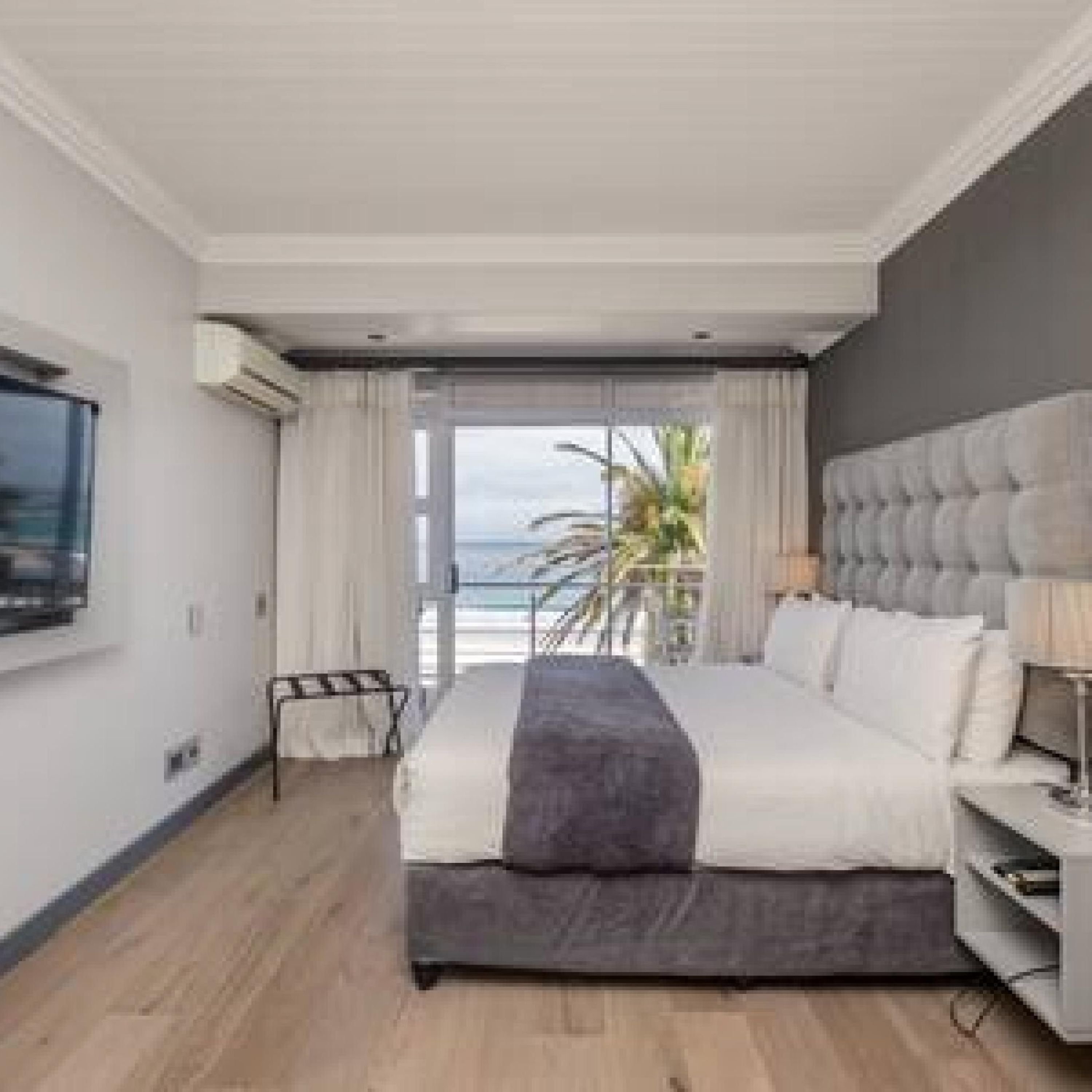 Een moderne slaapkamer met een groot bed, een televisie en uitzicht op zee.