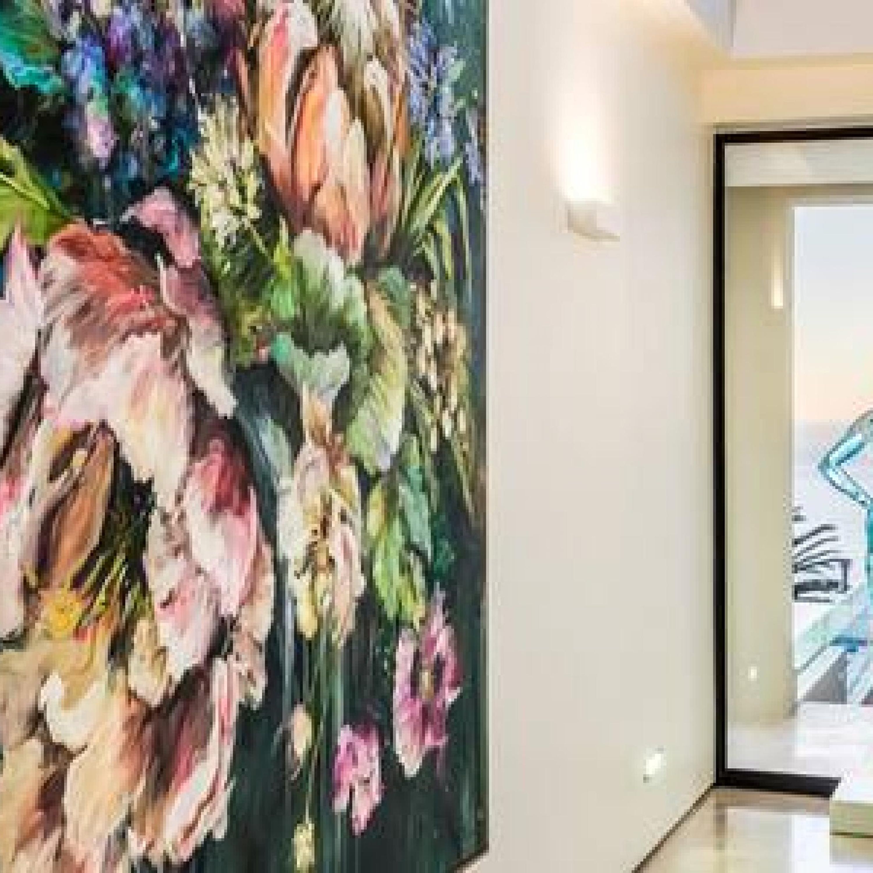 A room with a large floral painting on the wall and a view of a cityscape through the window.