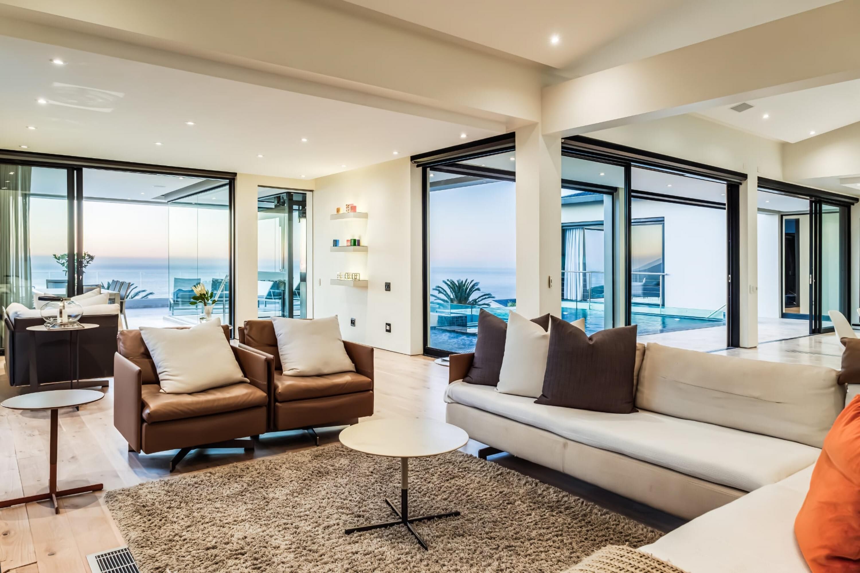Una sala de estar moderna con un sofá grande, una mesa de centro y vista al océano a través de ventanales.