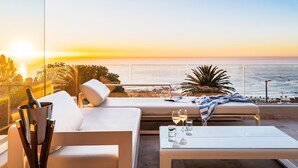 A sunlit terrace with a white sofa, a small table with glasses, and a bottle of champagne. - Spectacular Holiday Villa w Private Pool Gym Prima Views (Cape Town)