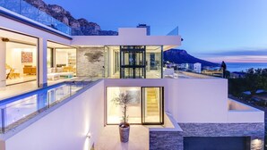 A modern multi-story house with a pool, glass doors, and a view of the sea and mountains. - Spectacular Holiday Villa w Private Pool Gym Prima Views (Cape Town)