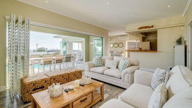 A spacious living room with a sofa set, a coffee table, and a view of a swimming pool.