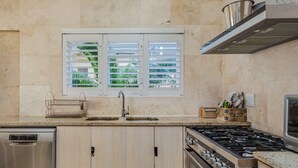 A modern kitchen with a built-in dishwasher, a gas stove, and a window with blinds.