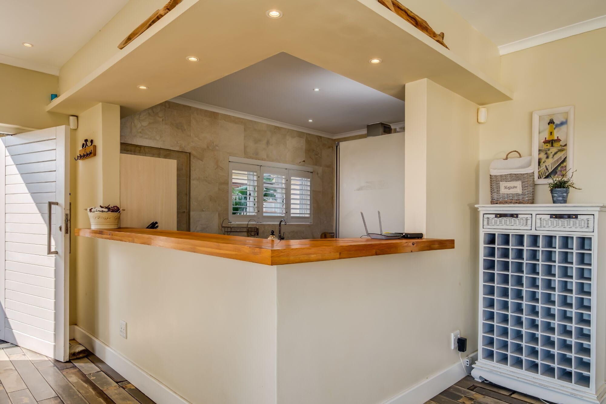 A kitchen with a wooden island, a white cabinet with a grid of drawers, and a window with blinds.