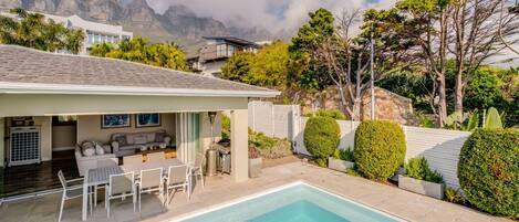 Una casa moderna con piscina, area relax esterna e vista sulle montagne.