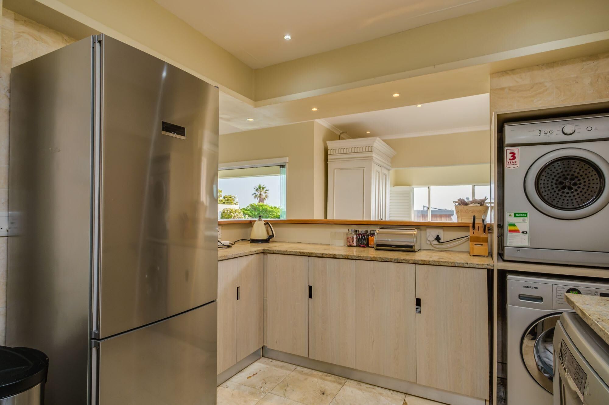 A modern kitchen with stainless steel appliances, wooden cabinets, and a built-in washer and dryer.