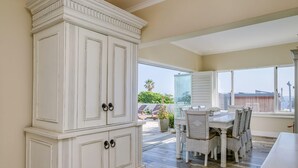 A dining area with a white cabinet, wicker chairs, and a view of the outdoors.