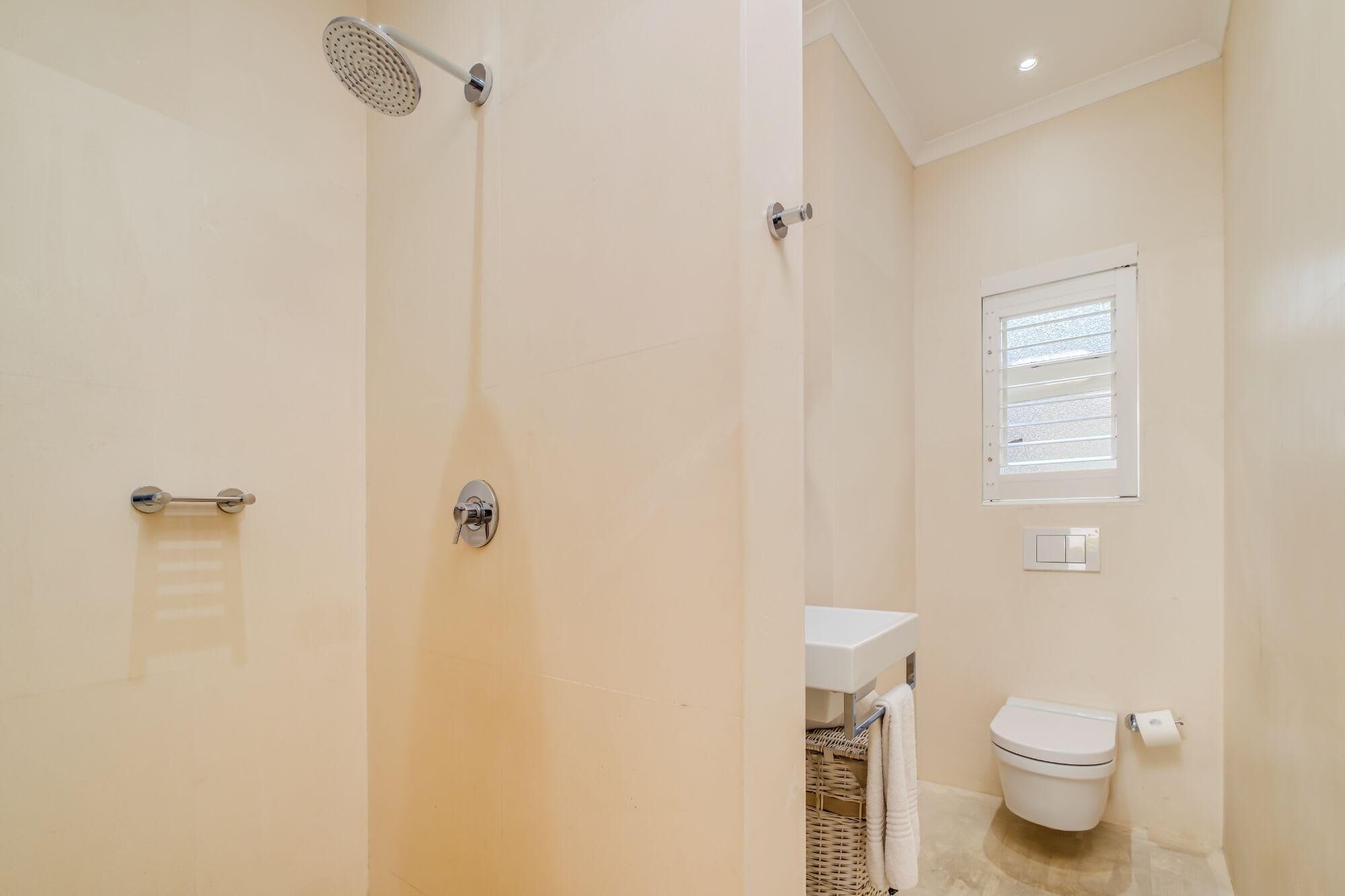 A bathroom with a shower, toilet, and a window.