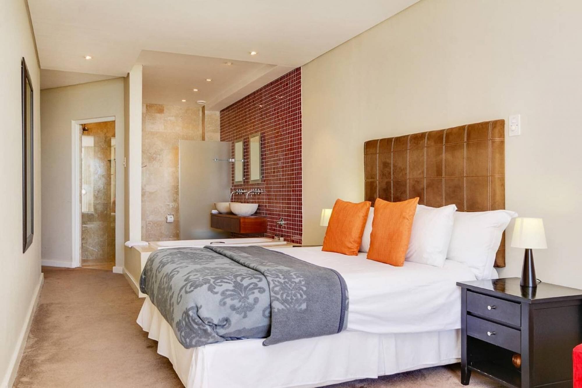 Un dormitorio moderno con una cama grande, una mesita de noche y otra mesilla.