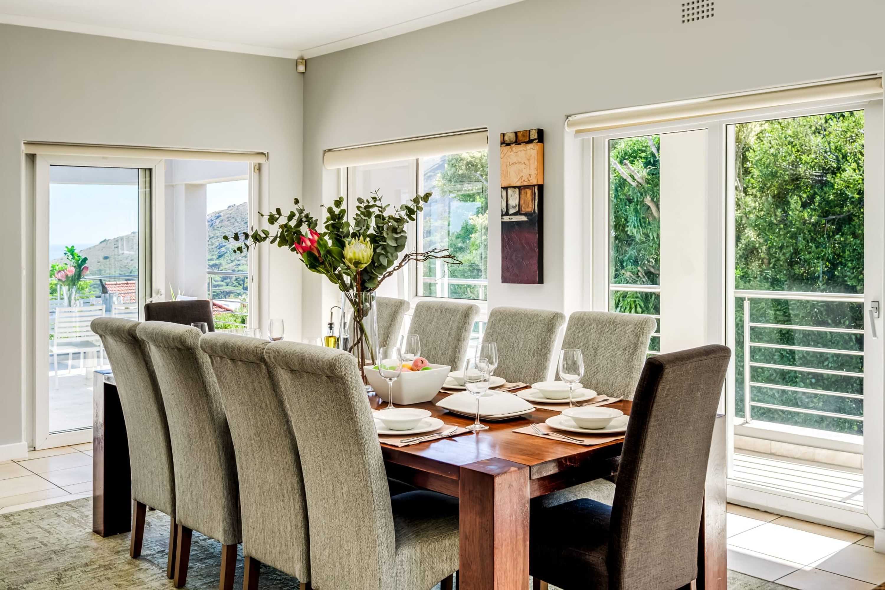 A dining area with a wooden table set for six, surrounded by six chairs.