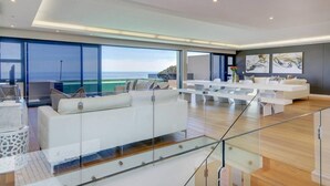 A modern living room with a glass railing, white furniture, and a view of the ocean. - Spacious Holiday Apartment With Fantastic Views Deck Pool Malindi (Cape Town)
