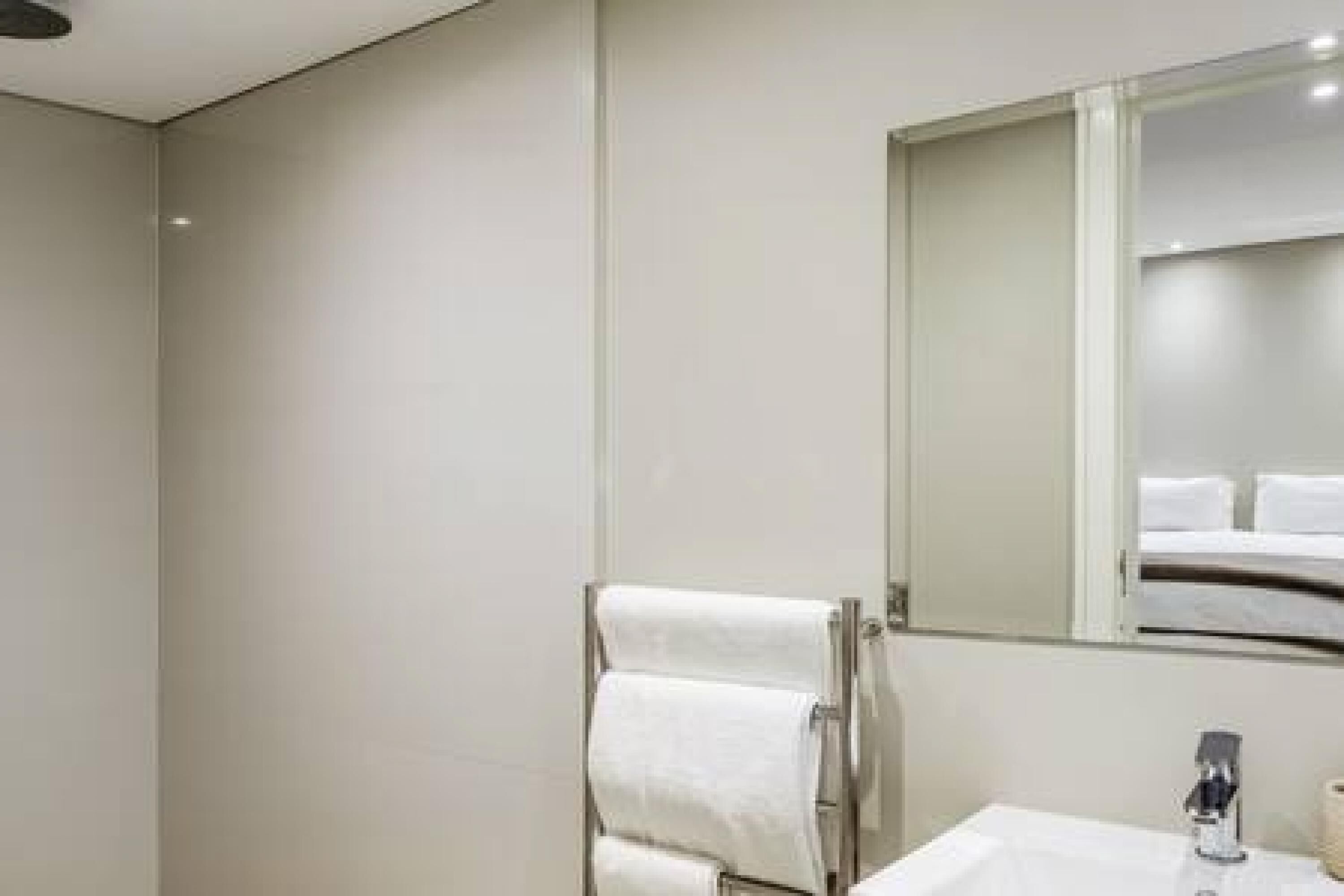 Een moderne badkamer met een grote spiegel, een handdoekrek en een wastafel.