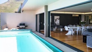 A modern interior with a pool, dining area, and a view of a mountain. - Spacious Holiday Apartment With Fantastic Views Deck Pool Malindi (Cape Town)