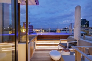 A rooftop terrace with a pool, wooden deck, and seating area.