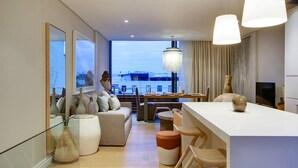 Un salon moderne doté d’une grande fenêtre, d’un coin repas et d’une cuisine.