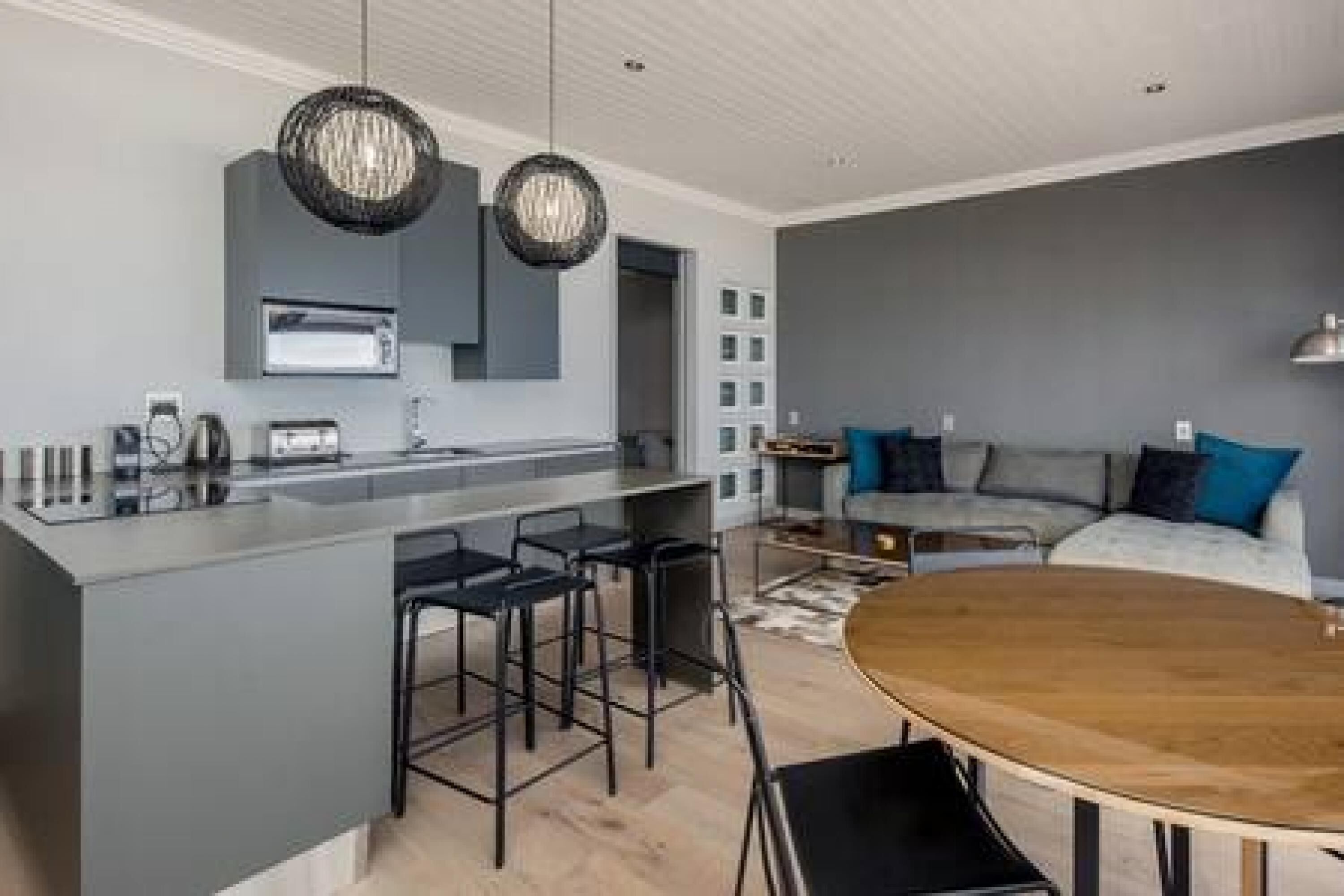 A modern kitchen with a central island, bar stools, and pendant lighting.