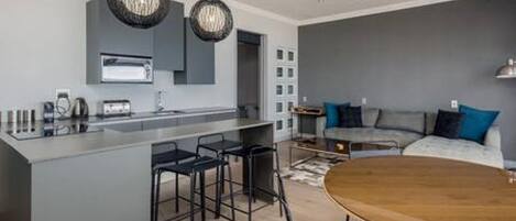 A modern kitchen with a central island, bar stools, and pendant lighting.