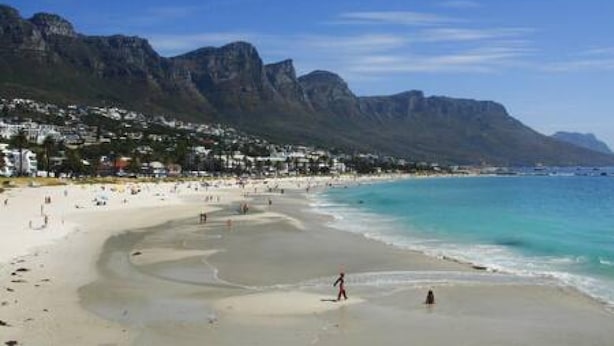 A beach with a mountain backdrop, sandy shores, and a few people. - Holiday Apartment Opposite the Beach Seasonsfind the Sunset (Cape Town)