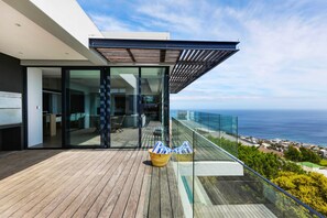 A modern balcony with glass railings overlooking the sea.