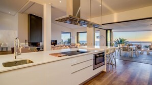 A modern kitchen with a large island, stainless steel appliances, and a view of the ocean. - Incredible Villa w Lap Pool Ocean Views Casa Di Sorrento (Cape Town)