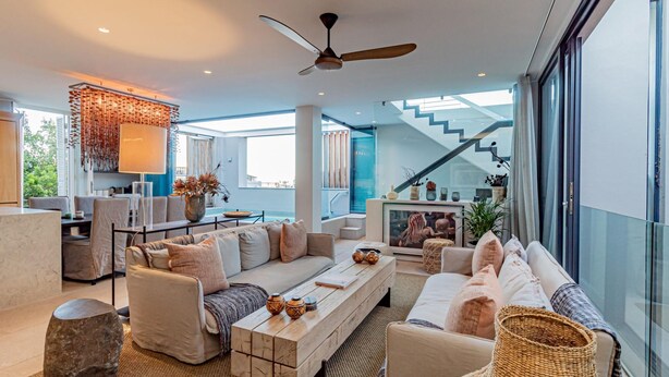 A spacious living area with a sofa set, a coffee table, and a dining table. There is a staircase leading to an upper level. - Stylish Apartment With Rooftop Deck Pool 53 Napier (Cape Town)