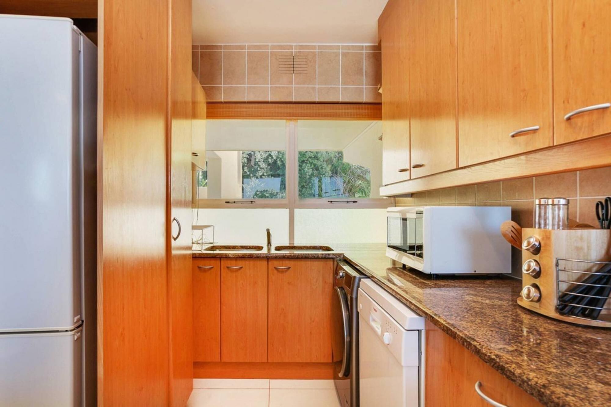 A kitchen with wooden cabinets, a sink, a dishwasher, a microwave, and a toaster.