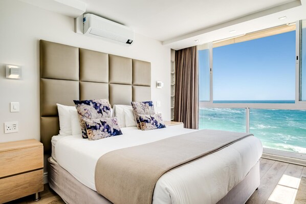 Une chambre d’hôtel moderne avec un grand lit, une vue sur l’océan et un balcon.